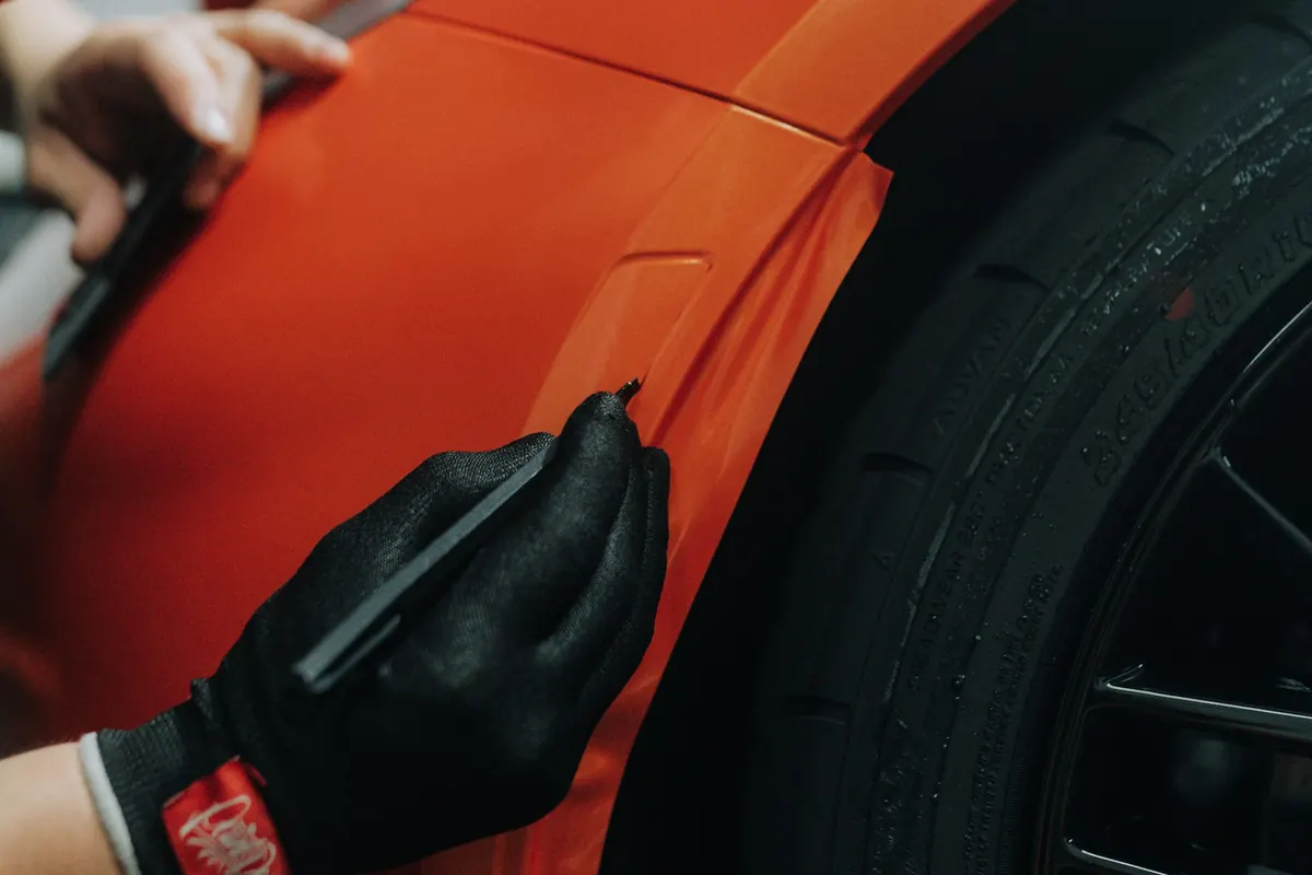 Folie wordt met handschoenen op een auto aangebracht